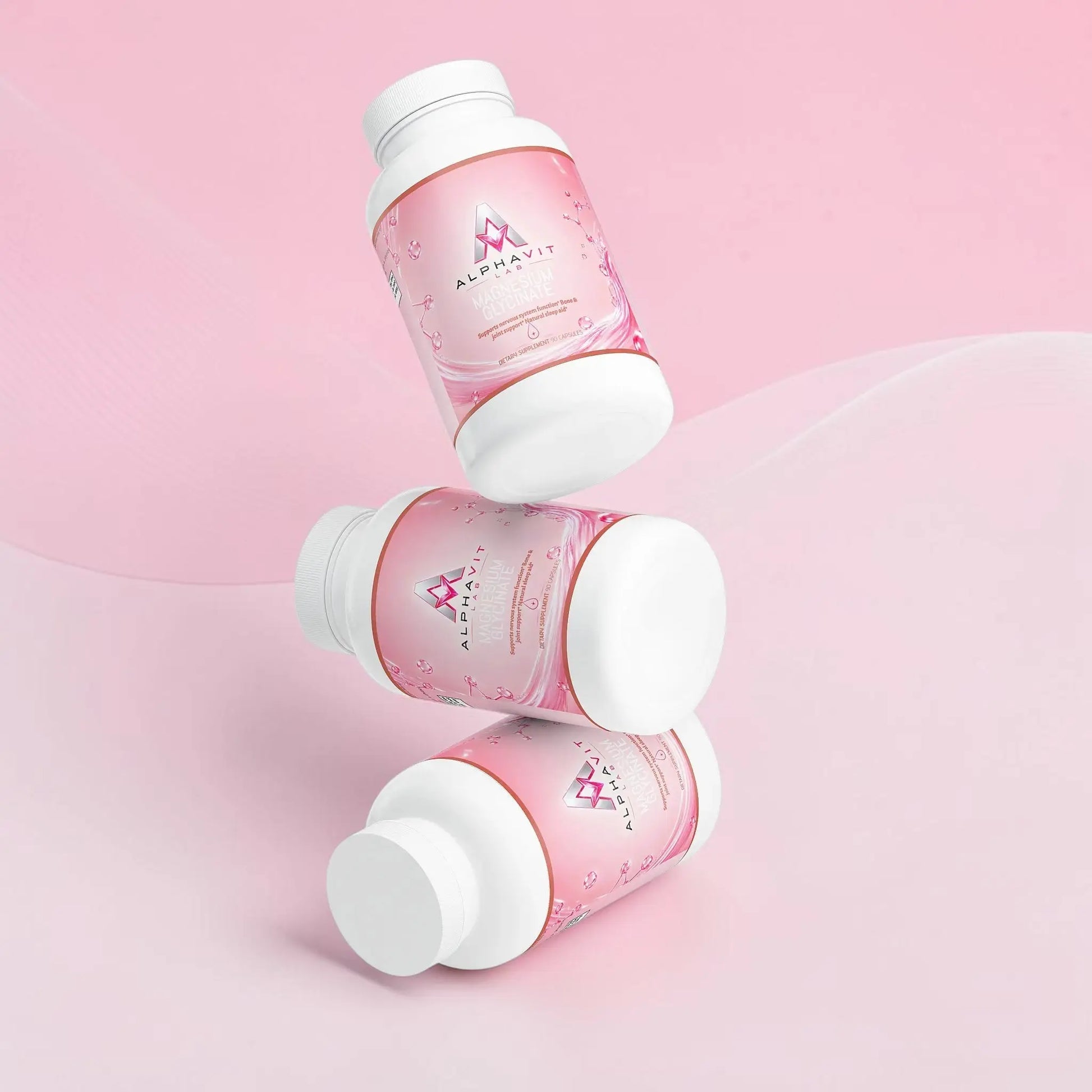 Trois flacons de supplément AlphaVIT Magnésium Glycinate flottant sur fond blanc, étiquettes roses et blanches.